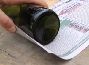 Newspaper being rolled around a wine bottle