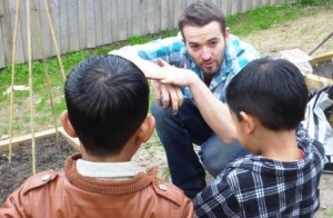 Demonstrating to the children some roots growing under the soil using hand gestures